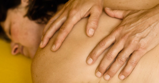 Physiotherapie bedeutet Berührung. Therapierende Hände auf dem Rücken einer Patientin von Physico, Physiotherapie in Köln Sülz Klettenberg